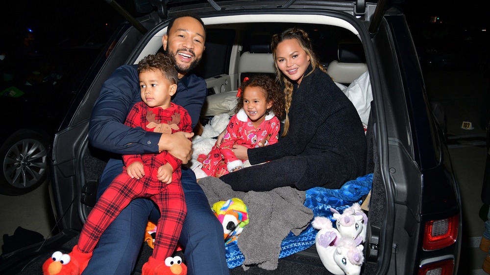 John Legend and Chrissy Teigen smiling with kids