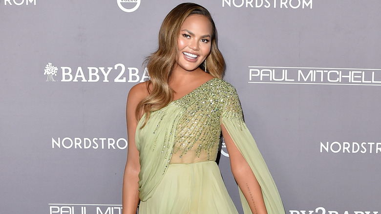 Chrissy Teigen smiling in green dress