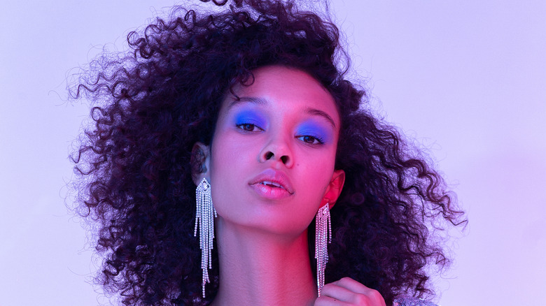 woman models '80s-inspred jewelry and blue eyeshadow