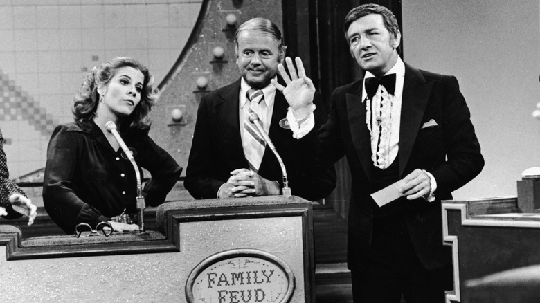 Richard Dawson holds up his hand on the set of Family Feud from April 1978 with the cast of Eight is Enough during a celebrity guest special