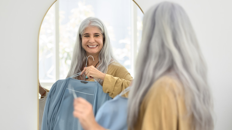 Woman holding up shirt in front of the mirror and smiling