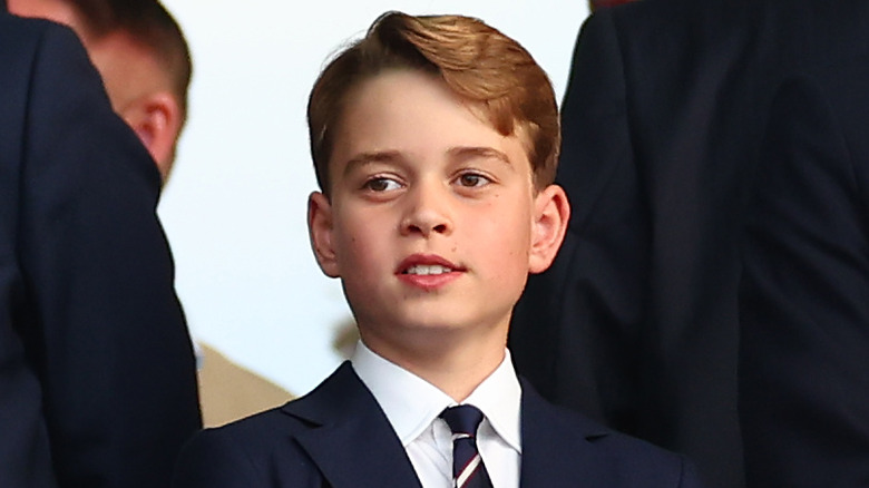 A smiling Prince George dressed in a suit