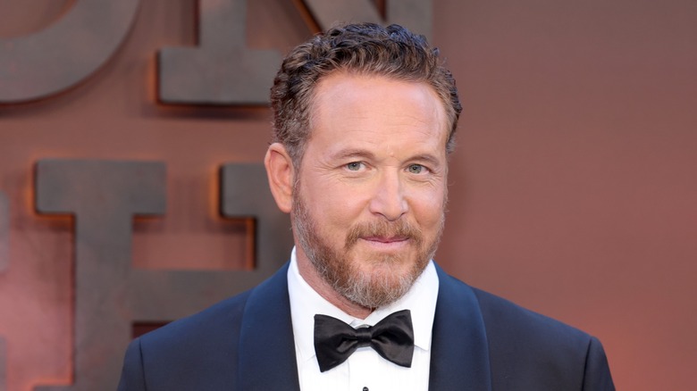 Cole Hauser posing and smiling, wearing a blue suit and black bow tie.