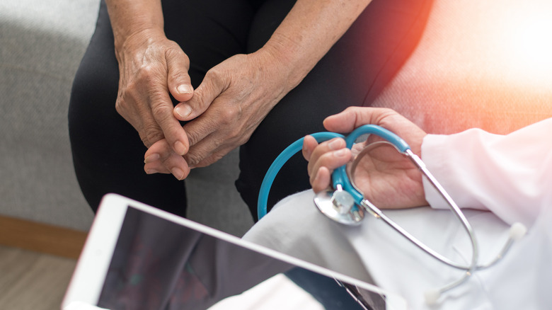 Person with folded hands sitting with a doctor 