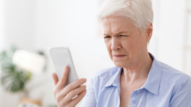 Older woman squinting at a phone screen