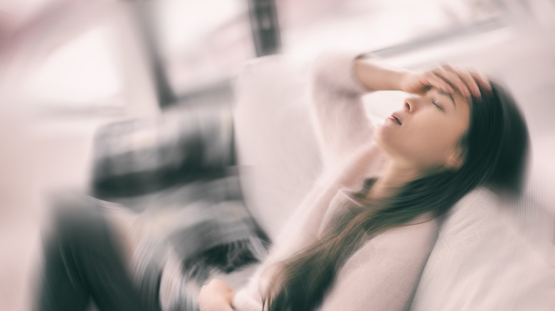 A woman holding her head in a spinning room 