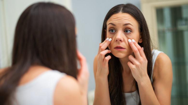 Woman checking her eyes in the mirror