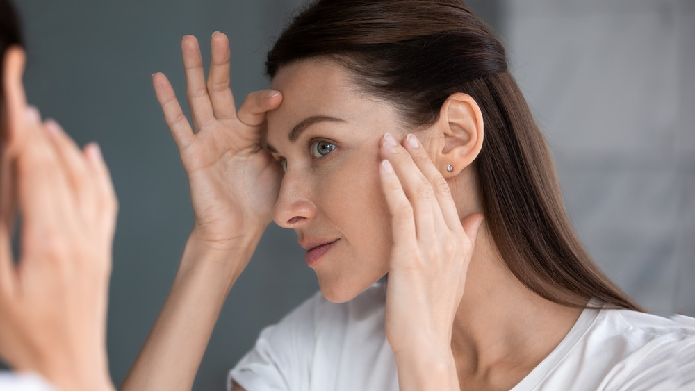 A woman examining her skin in the mirror 