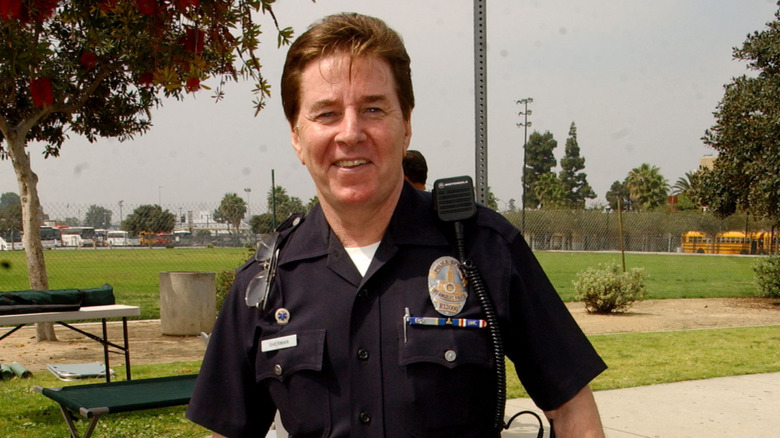 Bobby Sherman in dark police uniform with a shoulder radio.