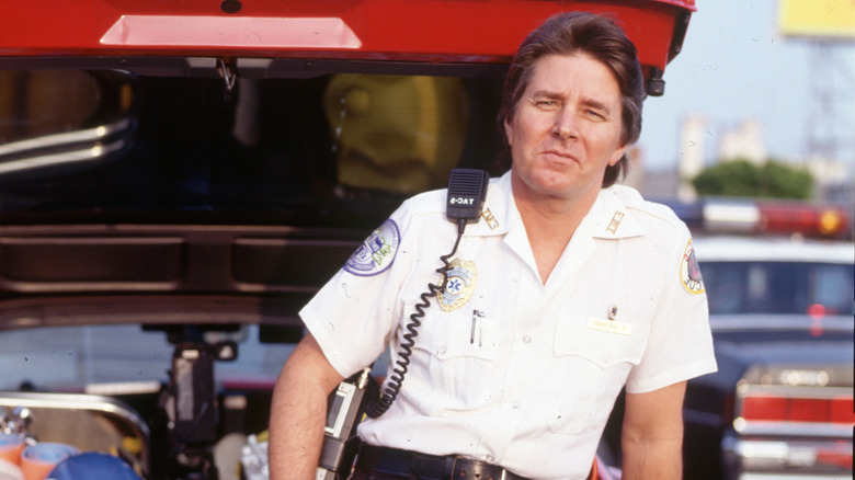 Sherman in a white paramedic uniform standing beside an emergency vehicle.