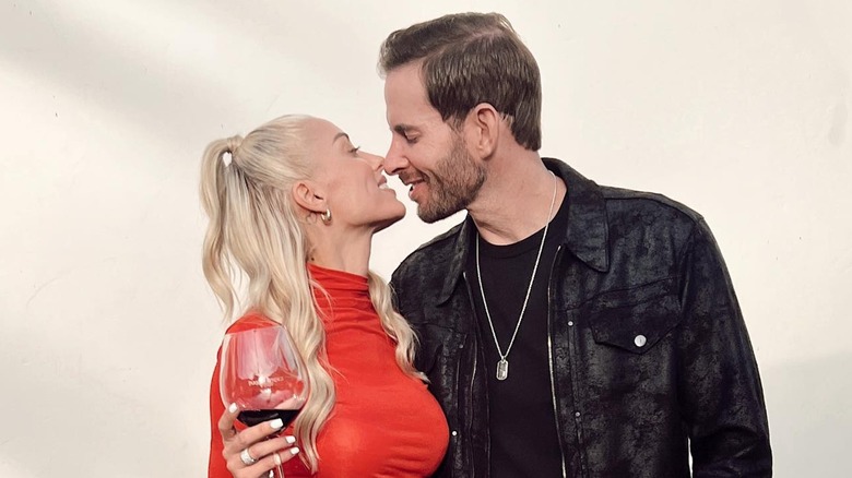 Tarek and Heather Rae El Moussa going in for a kiss as she hold a glass of red wine