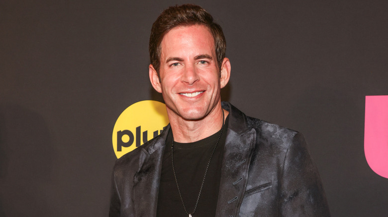 Tarek El Moussa smiling at an event in a black jacket and black shirt