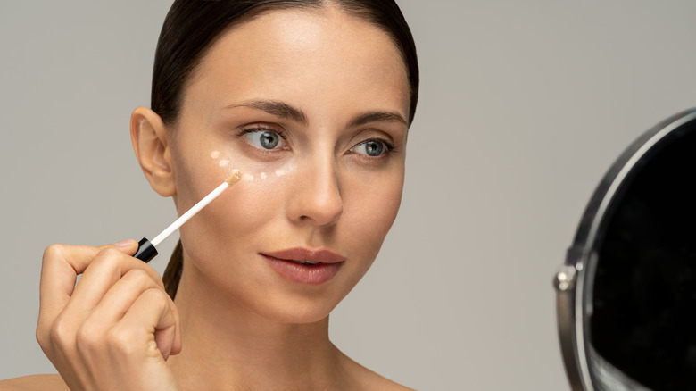 woman applying concealer under eye