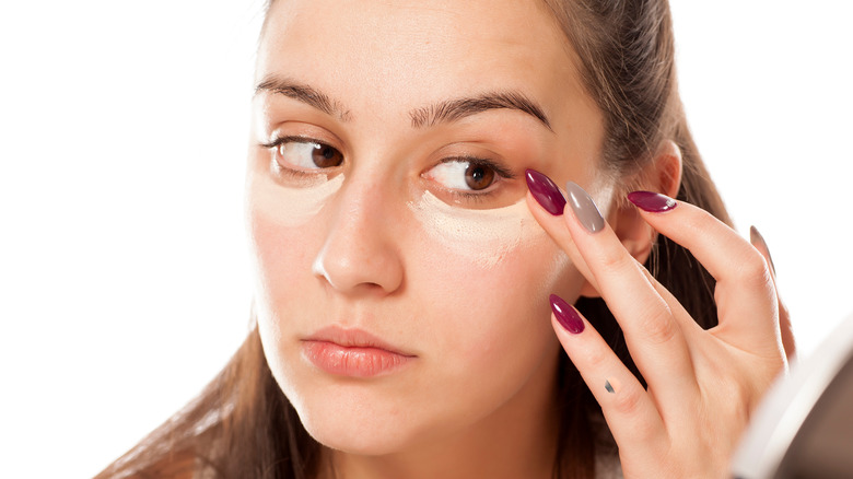 Woman applying brightener under eye