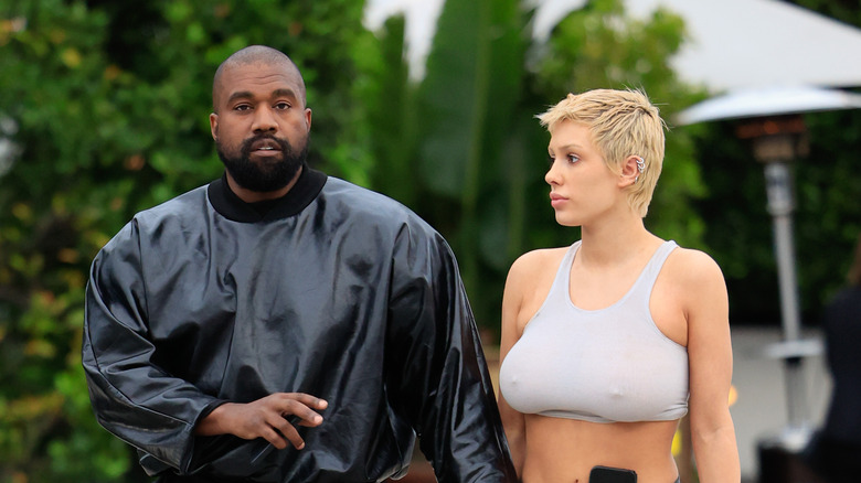kanye west and bianca censori hold hands while waling