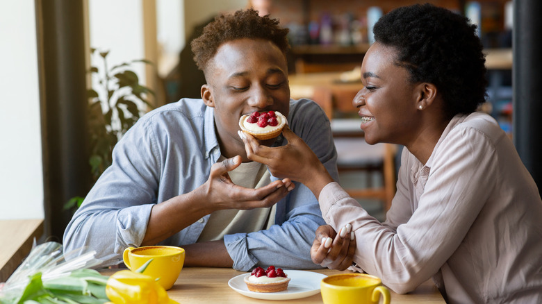 w oman feeds man pastry on a date