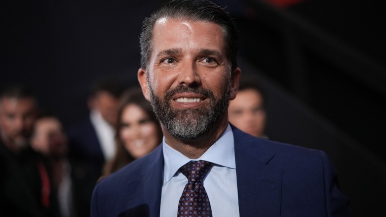 A close-up of Donald Trump Jr. with people standing behind him