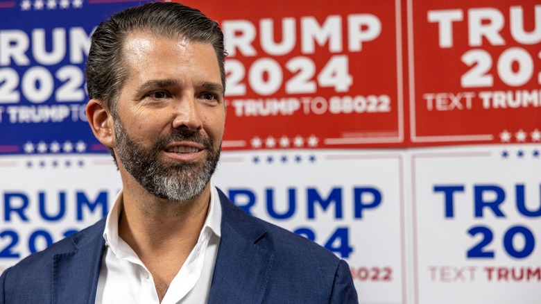 Donald Trump Jr. in front of a number of red, white, and blue Trump 2024 campaign signs