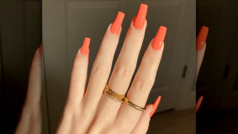 Woman with bright coral nails
