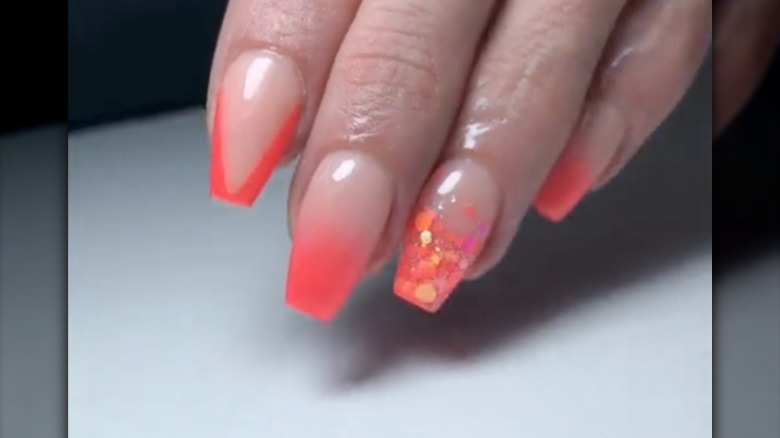 Nails painted with neon coral polish