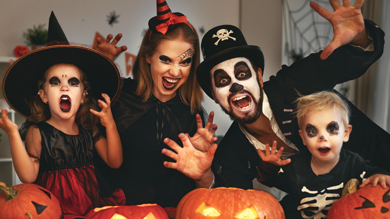 A family in Halloween costumes posing with pumpkins 