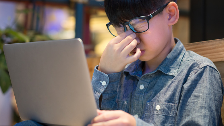 Boy looking at a screen with tired eyes