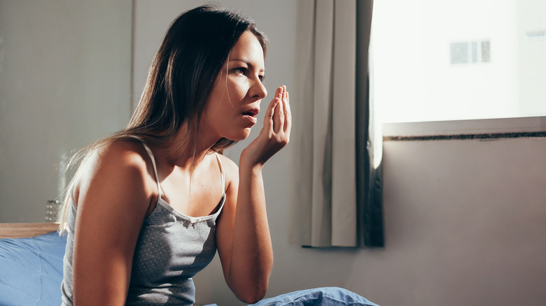 Woman checking her breath in the morning while in bed