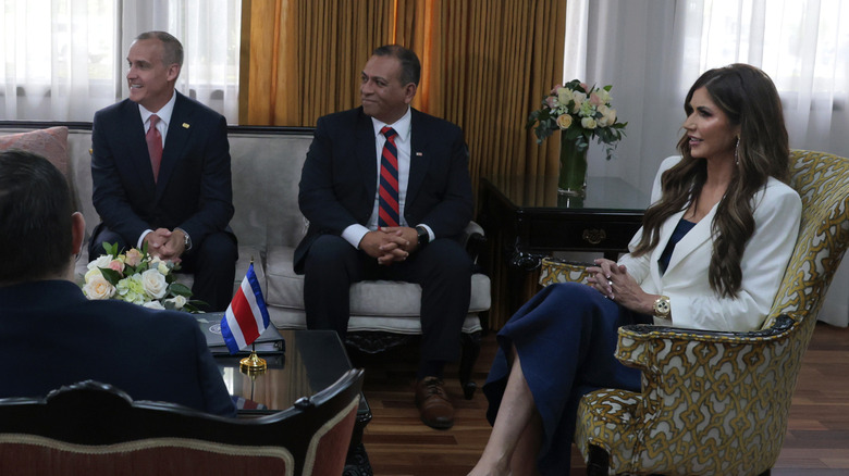 Corey Lewandowski and Kristy Noem talking and sitting with a group of people