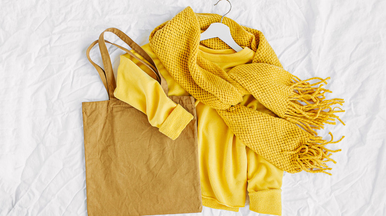 A yellow scarf, sweater, and handbag