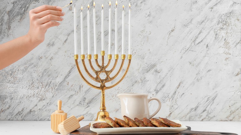 A plate of latkes by a lit menorah 