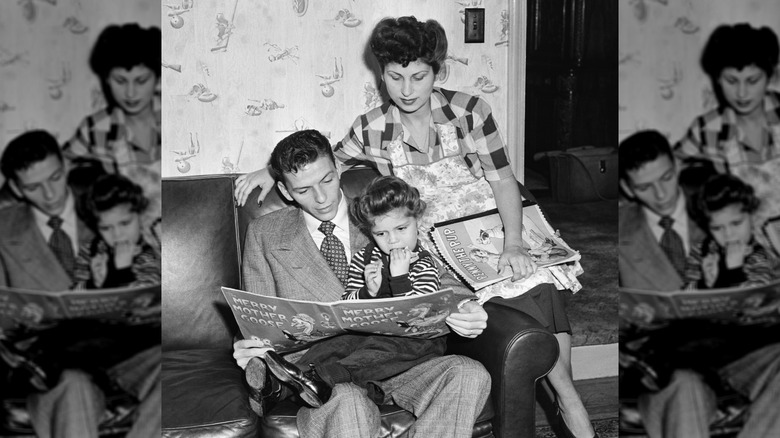 Frank Sinatra reads a book to his daughter, Nancy, as his wife, Nancy, looks on.