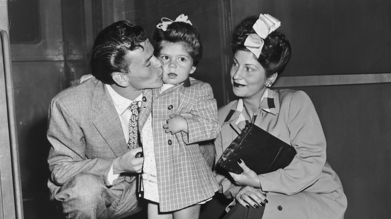 Frank Sinatra kisses his daughter on the cheek on a subway platform.