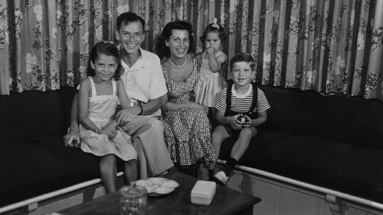 The Sinatra family - Nancy Jr., Frank, Nancy, Tina, and Frank Jr, - all sittiing on the couch.