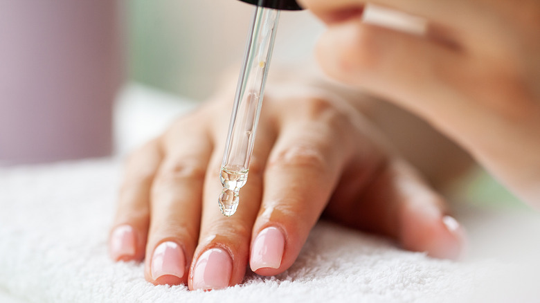 Woman putting cuticle oil on her hand