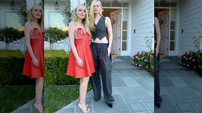 Dakota Fanning in a short red dress with a fake red flower covering one breast, standing outside with Elle Fanning