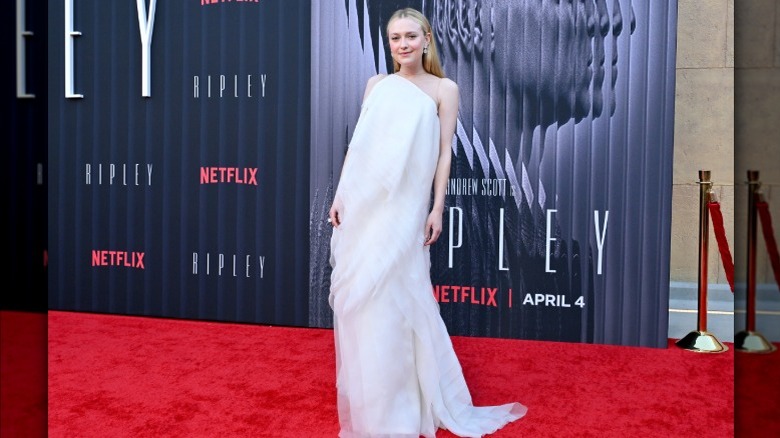 Dakota Fanning on the red carpet wearing a gauzy white gown with lots of fabric