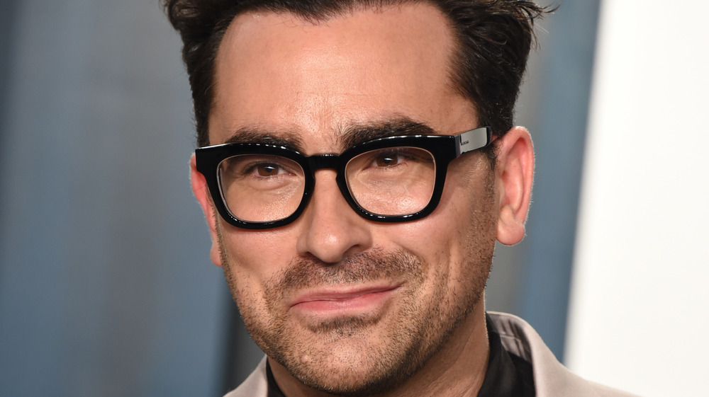 Dan Levy smiling, black-rimmed glasses