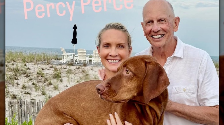 Dana Perino and Peter McMahon posing on a beach with their large brown dog