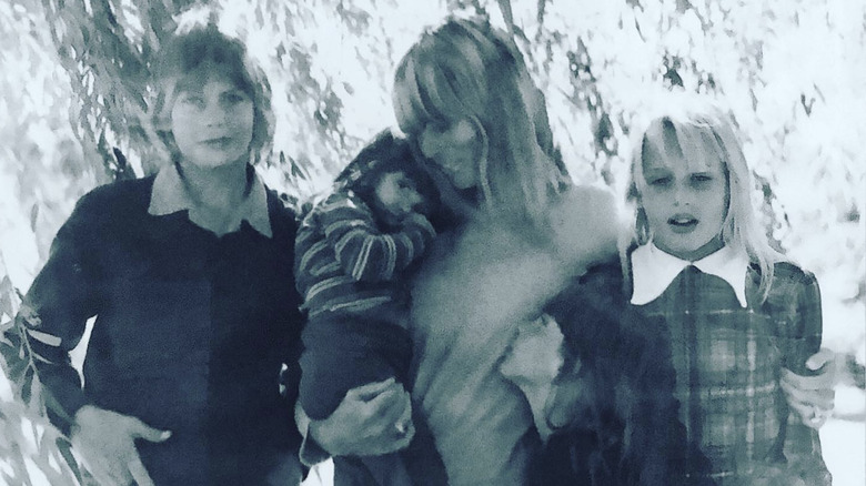 Daryl Hannah stands next to her mom and siblings as a young child outside in a black and white photo