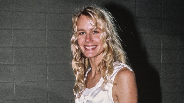 Actor Daryl Hannah with curly hair walks in a white tank top dress smiling