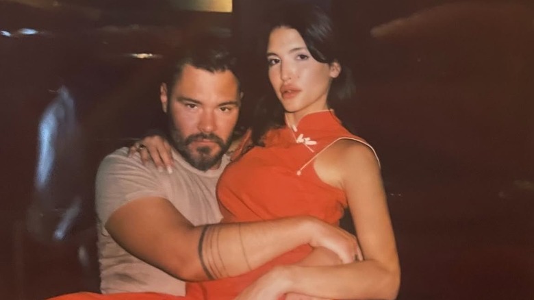 Reem Amara sitting in Patrick John Flueger's lap with her arm around his shoulders.
