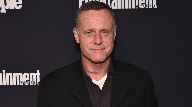 Jason Beghe smiling in a black coat.