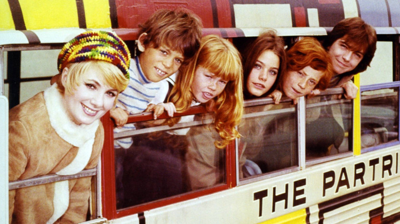 The cast of 'The Partridge Family' sticking their heads out the windows of their bus
