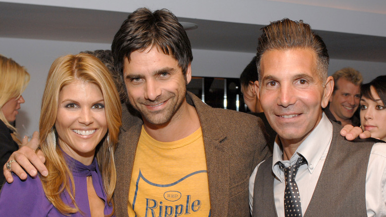 John Stamos posing with his arms around Lori Loughlin and Mossimo Giannulli