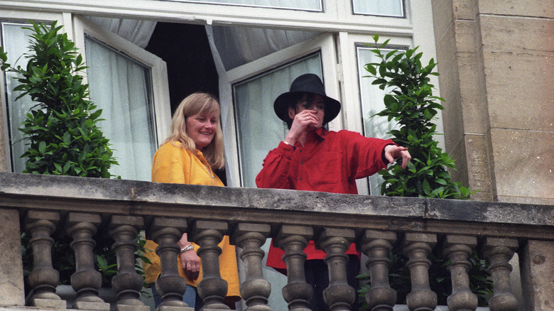 Debbie Rowe and Michael standing and pointing on a balcony.