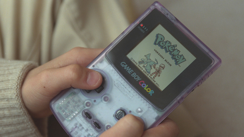 A person playing Pokémon on a Game Boy Color