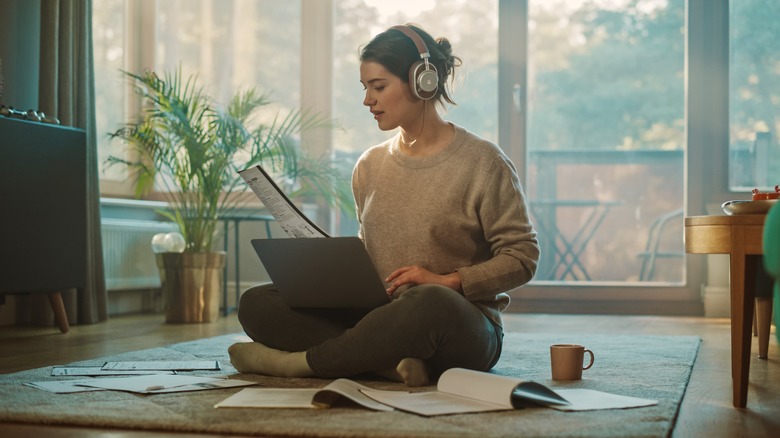 woman sitting on ground laptop headphones on