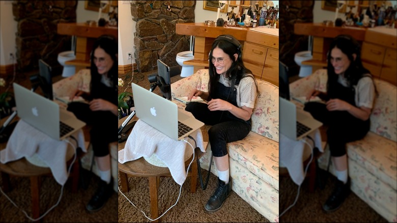 Demi Moore sitting on a couch and looking at her laptop