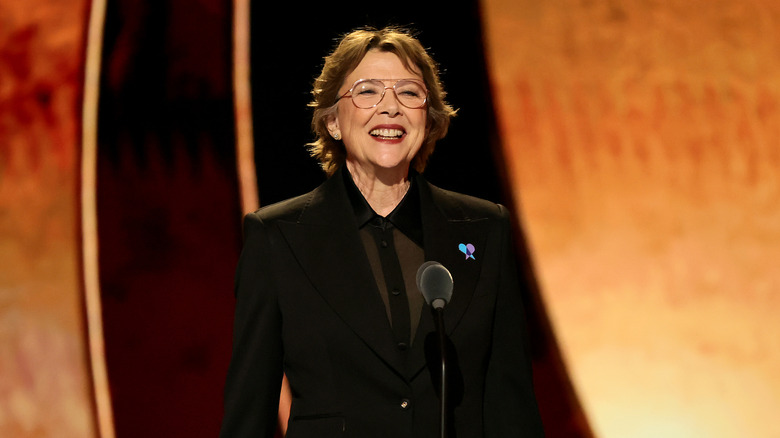 Annette Bening in a black tux before a mic