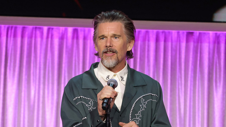 Ethan Hawke in a green coat and shirt with his initials